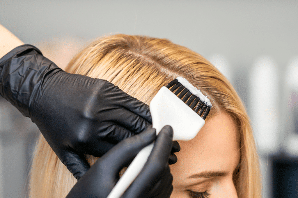 Hair Coloring 2 Stylist adding hair coloring to the roots of a blond haired woman.