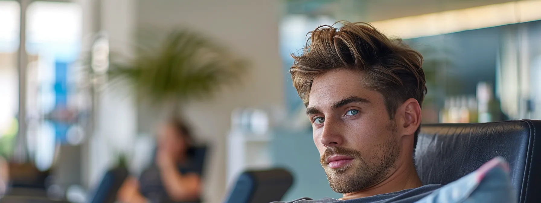 Mastering Fade Haircut Maintenance: A Comprehensive Guide 2 a man sitting confidently in a salon waiting room with a faded hair style waiting to have his fade touched up