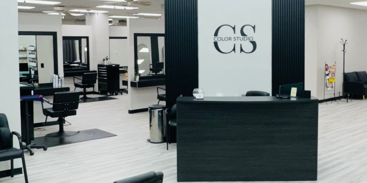 Lobby of the Color Studio and Salon showing a black desk with a slat wall and the CS logo behind it.