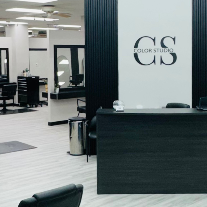 Lobby of the Color Studio and Salon showing a black desk with a slat wall and the CS logo behind it.